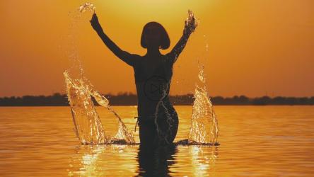 Silhouette of a woman in the pool against the sunset[]