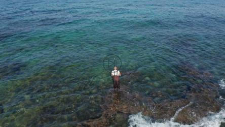 渔夫站在浅滩上划着线[]