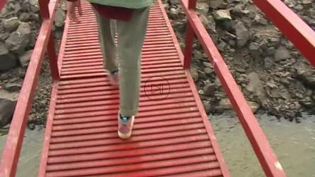 镜头跟随一名年轻女子走过一个红色金属码头[免费商用]