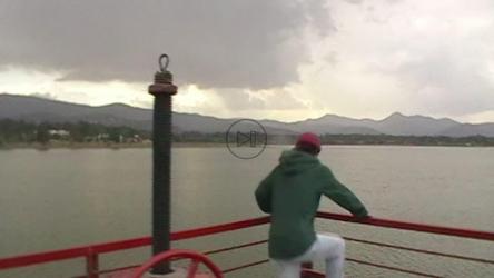 一名年轻男子爬上大坝栏杆，对着镜头摆姿势[免费商用]