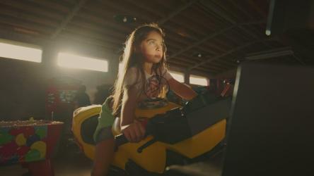 一个小女孩兴奋地骑着一辆街机摩托车[免费商用]