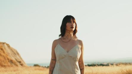 女人拿着一台老式相机走过阳光明媚的乡村[]