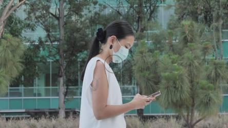 戴着口罩的女人边发短信边走路[免费商用]