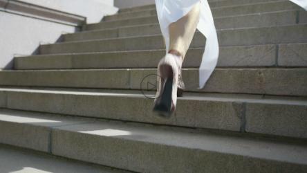 Close up of a woman wearing high heels running up the stairs[]