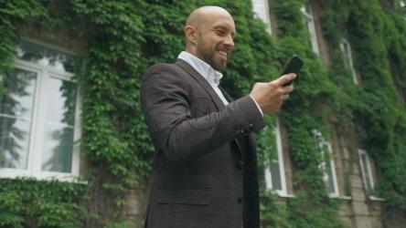 快乐的商人看着他的手机[]