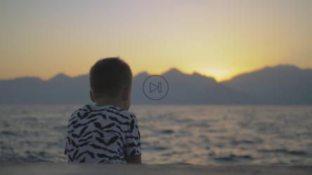 孤独的男孩坐在海边[]