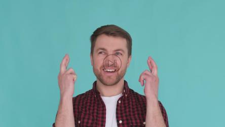 Young man holding fingers crossed and making wishes[]