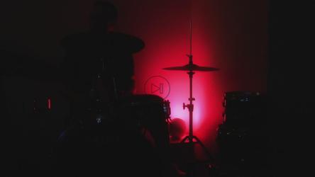 Playing drums in the dark under colored light[]