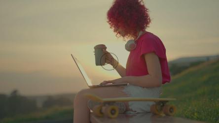 年轻女子在美丽的日落下户外工作[]