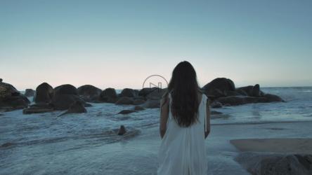 一名女子在海滩上走向巨石[免费商用]