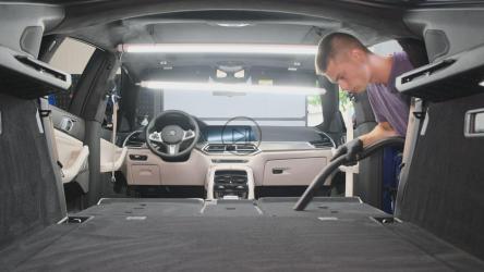 汽车清洁专业人员用吸尘器清洁汽车内部[]