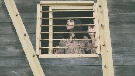 女孩从一间旧小屋的窗户向外窥视[免费商用]