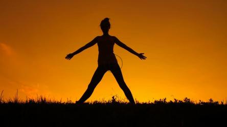 日落时一名女子做瑜伽的剪影[]