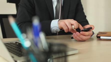 一名穿着西装的男子在办公室里用手机[]