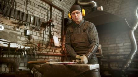 Young blacksmith in his workshop heating up a metal knife[4K]
