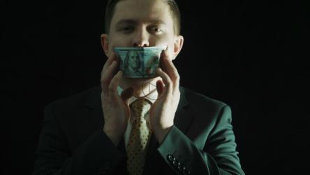 一个穿着西装的人把钱放在嘴里[]