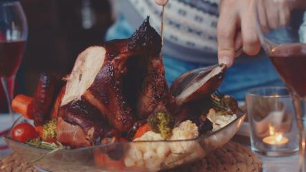 Close up of a chicken being carved at a family dinner[]