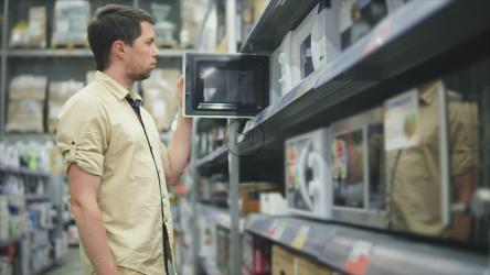 男子在家居商店比较不同的微波炉[]