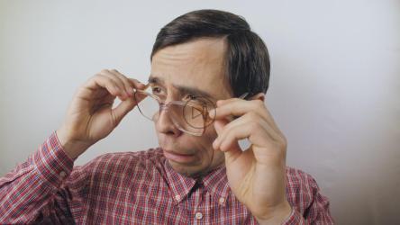 Confident nerdy man puts on his glasses[]