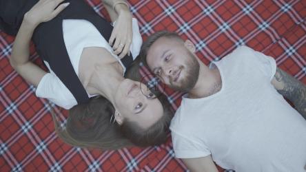 Couple laying over a blanket in the park[]