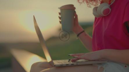 粉红色卷发女孩在日落中用笔记本电脑工作[]