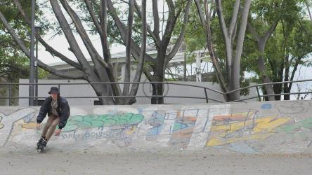 一名年轻男子穿着旱冰鞋滑下坡道，上面有涂鸦[免费商用]