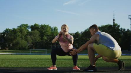 教练帮助一名女子进行深蹲训练[4K]