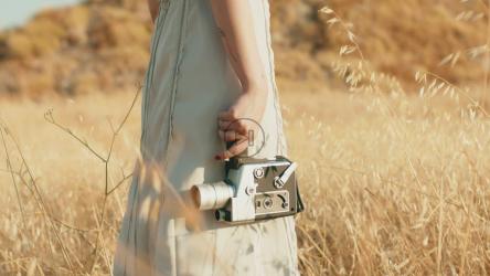 Standing in a field with a vintage camera about to film[]