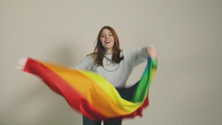 女孩用彩虹旗庆祝并跳舞[]