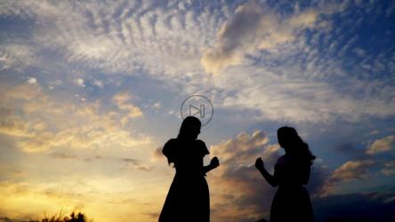 两个朋友在令人惊叹的日落天空下跳舞[]