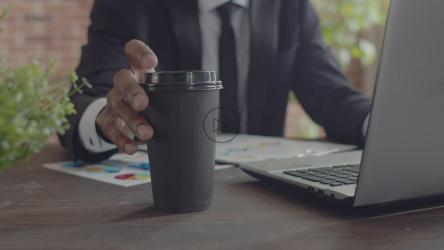 一名办公室工作人员在办公桌旁喝咖啡的特写镜头[]