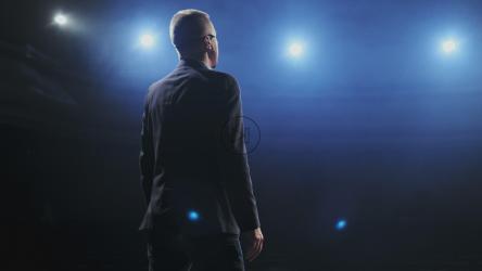 Speaker in suit speaks to his audience on stage[4K]