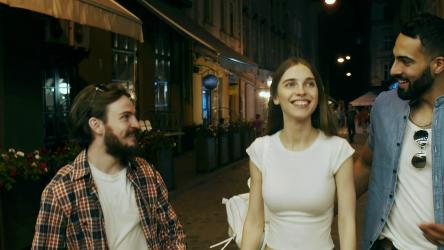 Friends laugh and walk down city street at night[]
