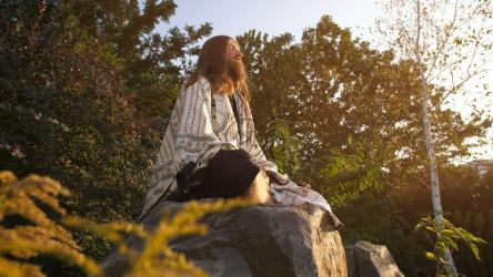 Long beard man meditating in nature[]