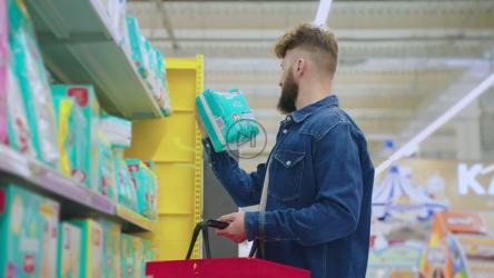 年轻爸爸在超市选购纸尿裤[]