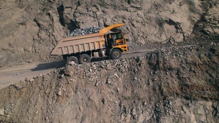 装满岩石的黄色大型自卸卡车在采石场行驶[]