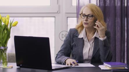 Woman in an office taking note during a phone call[]