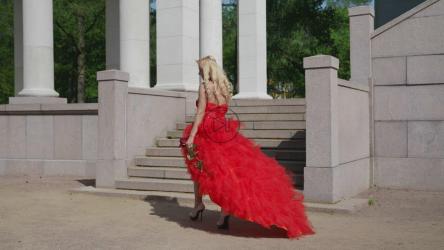 一个打扮成公主的女人，穿着红色连衣裙，手里拿着一朵玫瑰[]