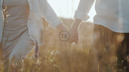 一对幸福的夫妇手牵着手穿过田野的特写[]