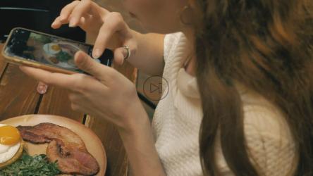 女孩在餐馆里给自己的食物拍照[免费商用]