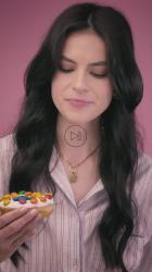 一位年轻女子在粉红色的背景上咬着一个甜甜圈[免费商用竖屏]