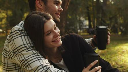 一位女士在公园里享受咖啡时拥抱着她的男朋友[]