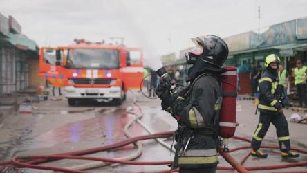 消防员在处理紧急情况，消防车在后面[]