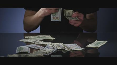 男子从桌子上捡起100美元钞票[]