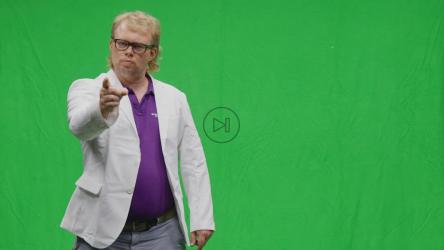 一名男子在绿色屏幕背景下指着摄像机[]