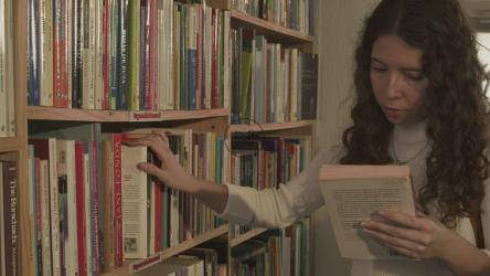 一位年轻的女学生把一本书还给图书馆的书架[免费商用]