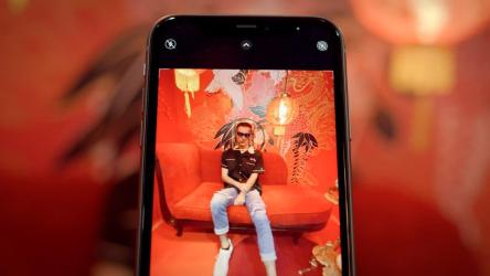 一个戴着墨镜的年轻人在一间红色瓷器主题的房间里对着小话筒摆姿势[免费商用]