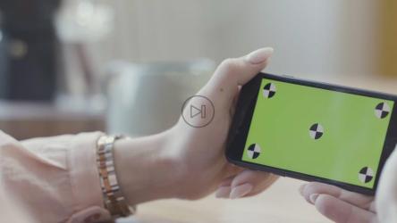 一名女子侧身拿着一部智能手机[]