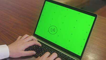 在绿色屏幕的笔记本电脑上打字的人[]