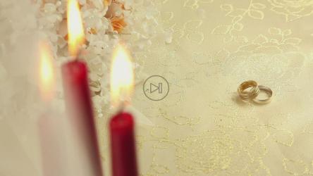 塑料花和蜡烛旁边的一对戒指[]